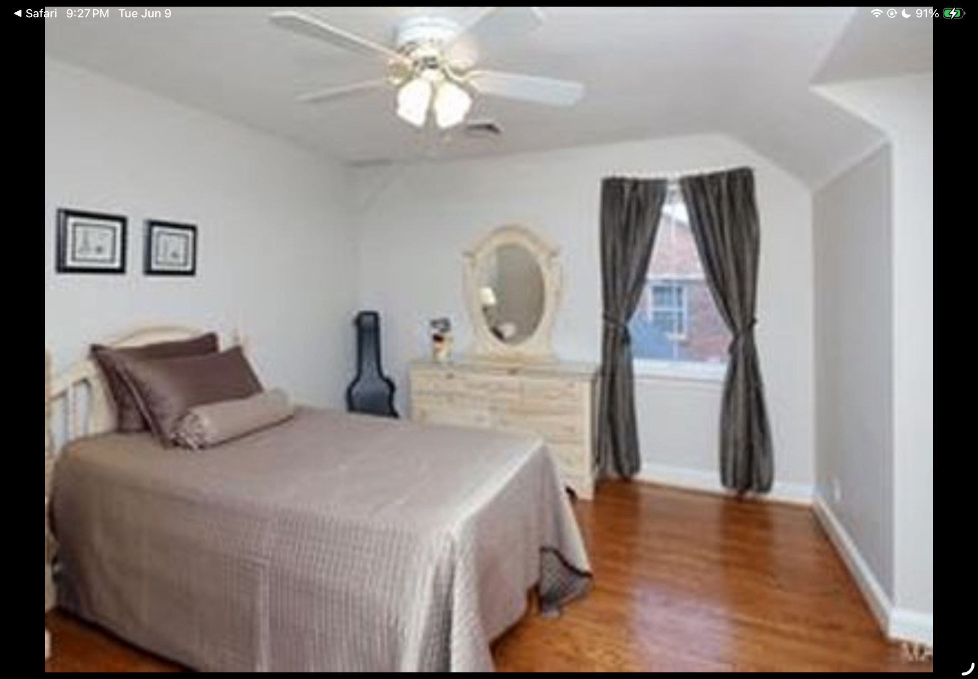 Bedroom with vaulted ceiling, hardwood floors and dresser beneath an oval mirror