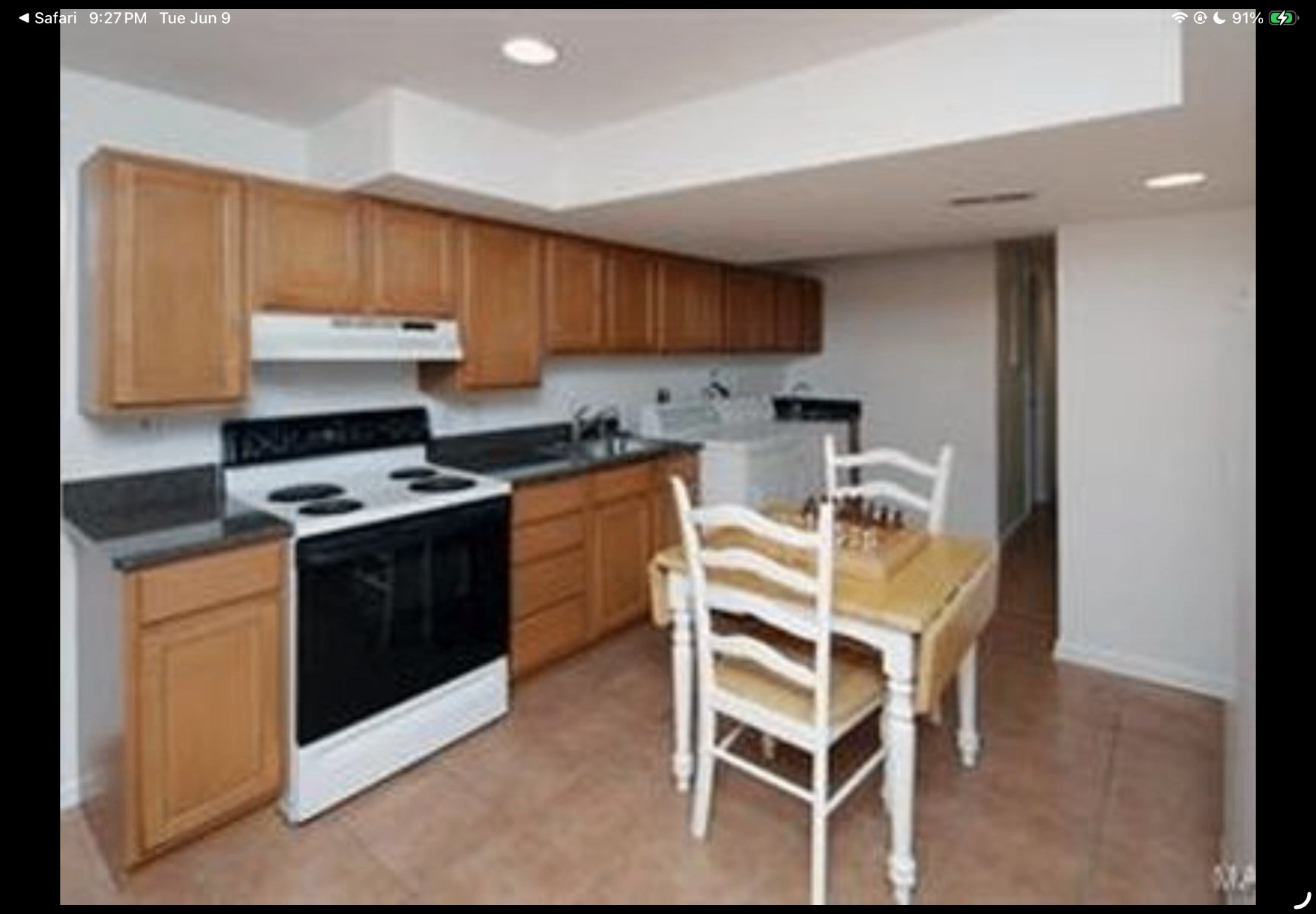 Lower-level kitchen with wood cabinetry, white range and breakfast table