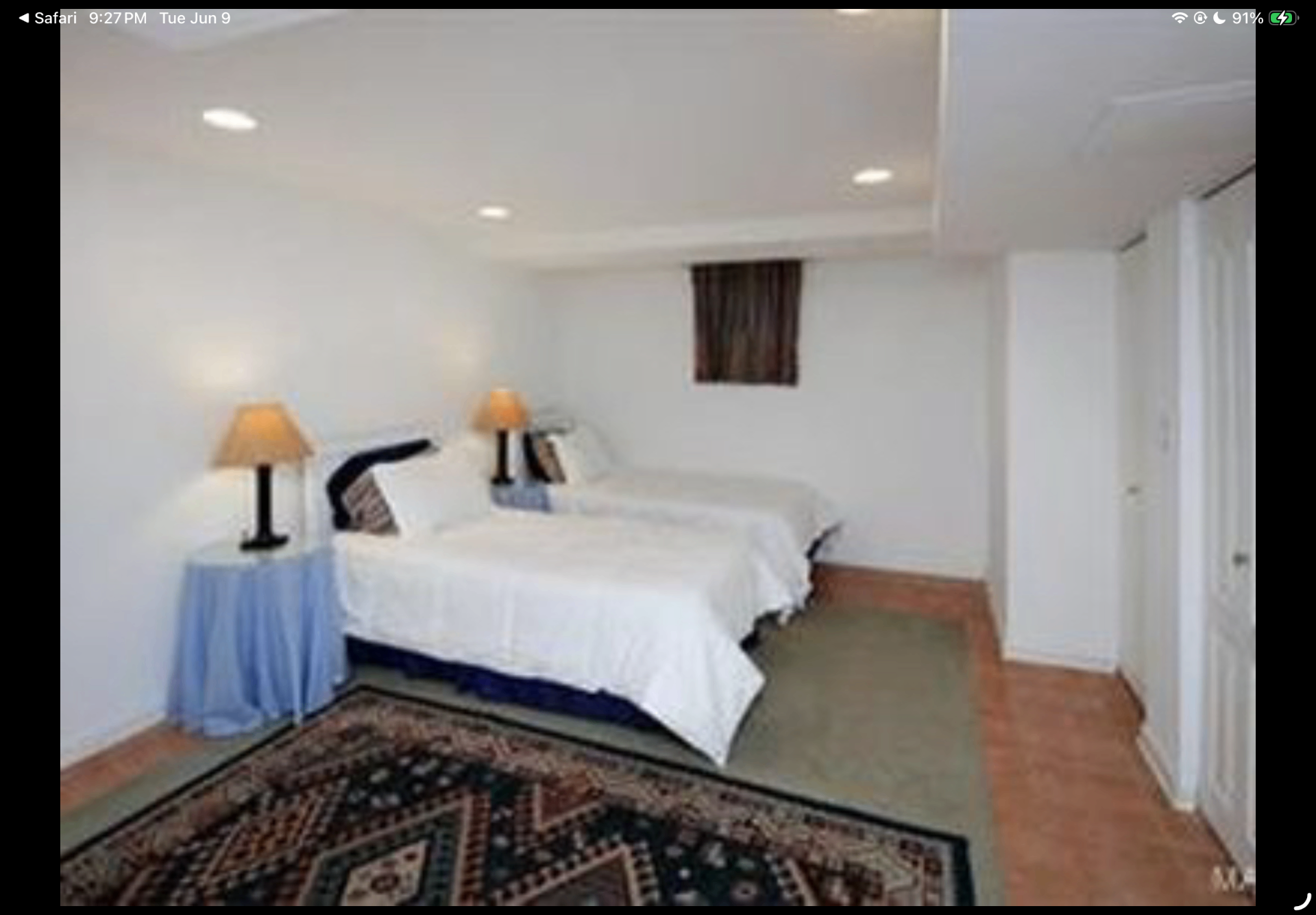 Guest bedroom with two twin beds, bedside lamps and a patterned rug
