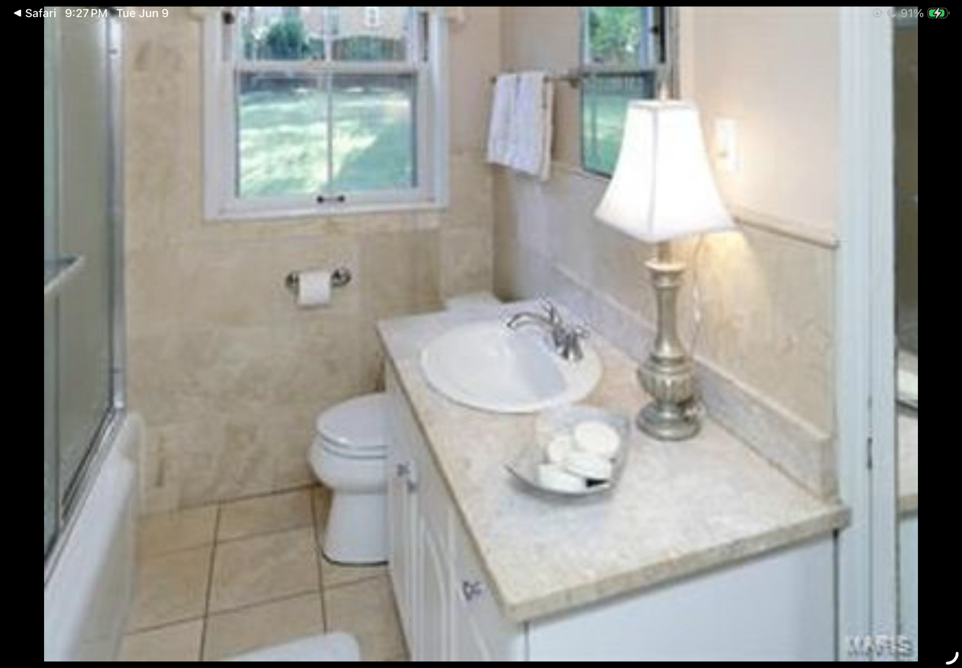 Bathroom with cream-toned vanity, lamp lighting and tiled shower enclosure