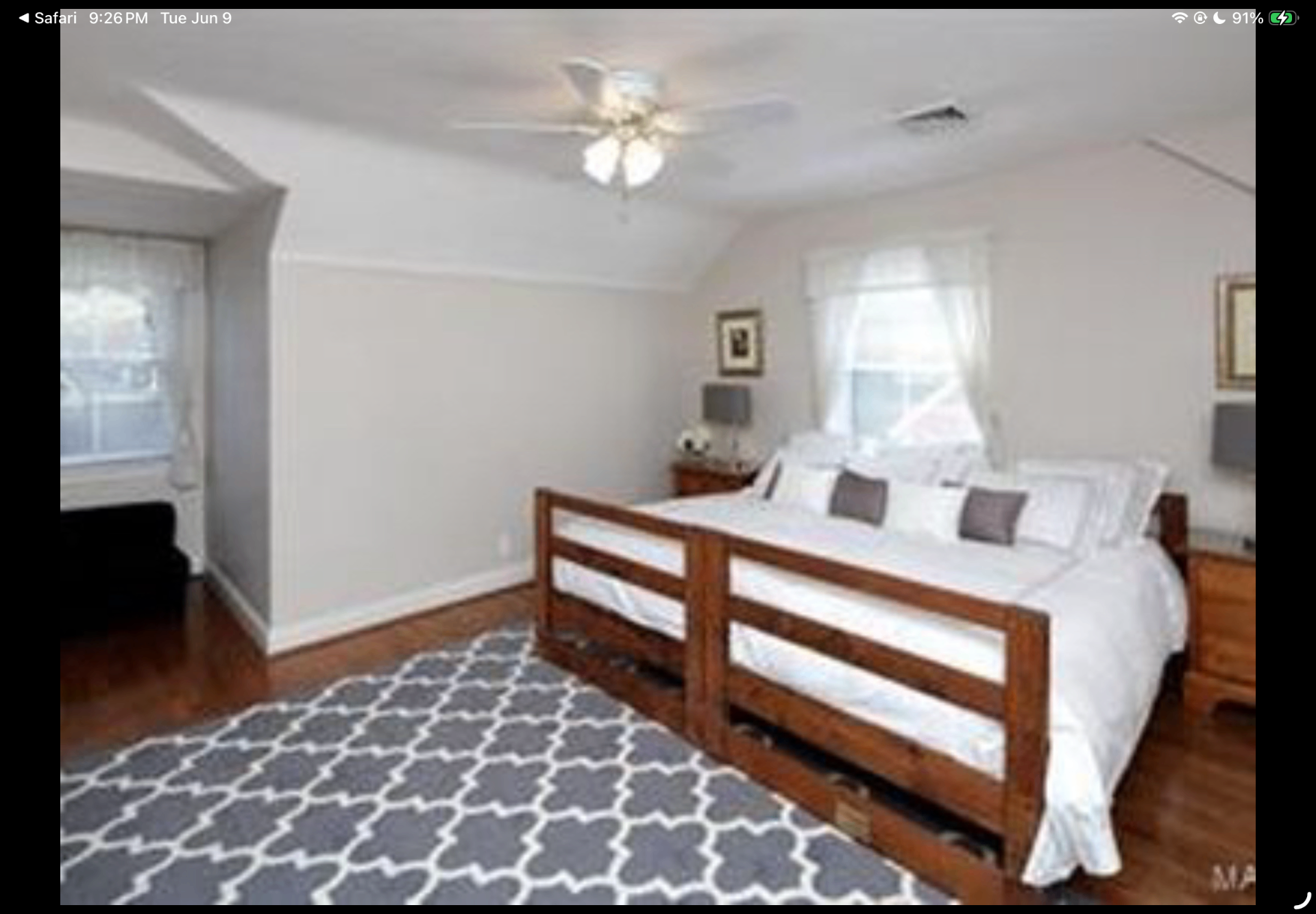 Bedroom with wood bed frame, hardwood floors and soft natural light