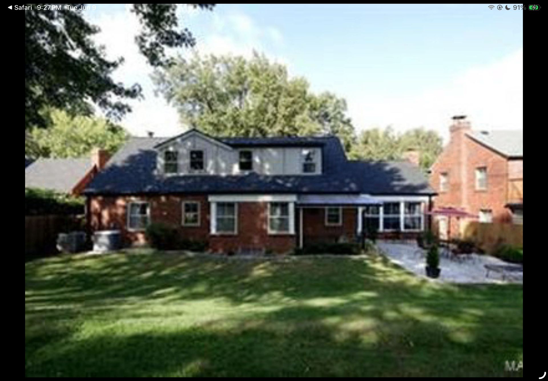 Rear exterior view of the brick home with sunroom addition and manicured lawn