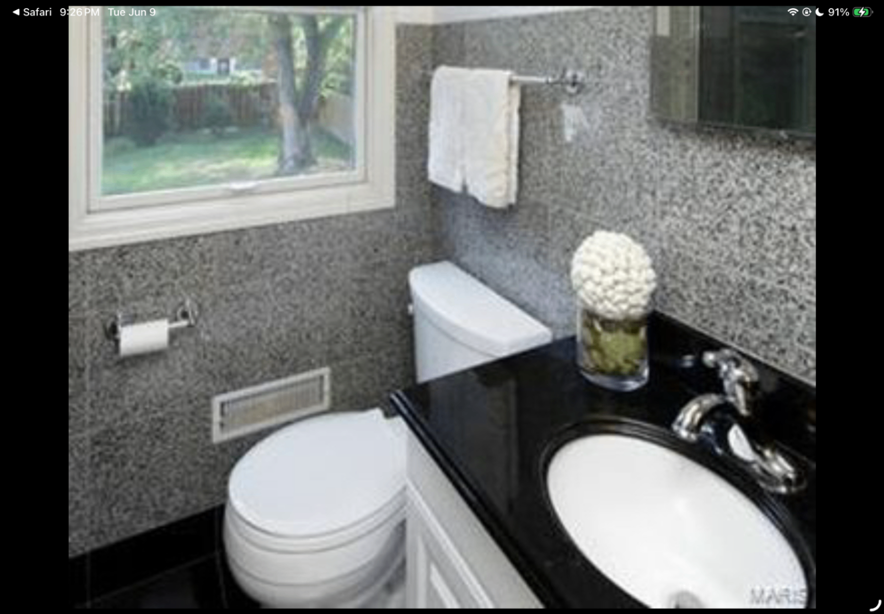 Bathroom with black vanity top, white fixtures and large window
