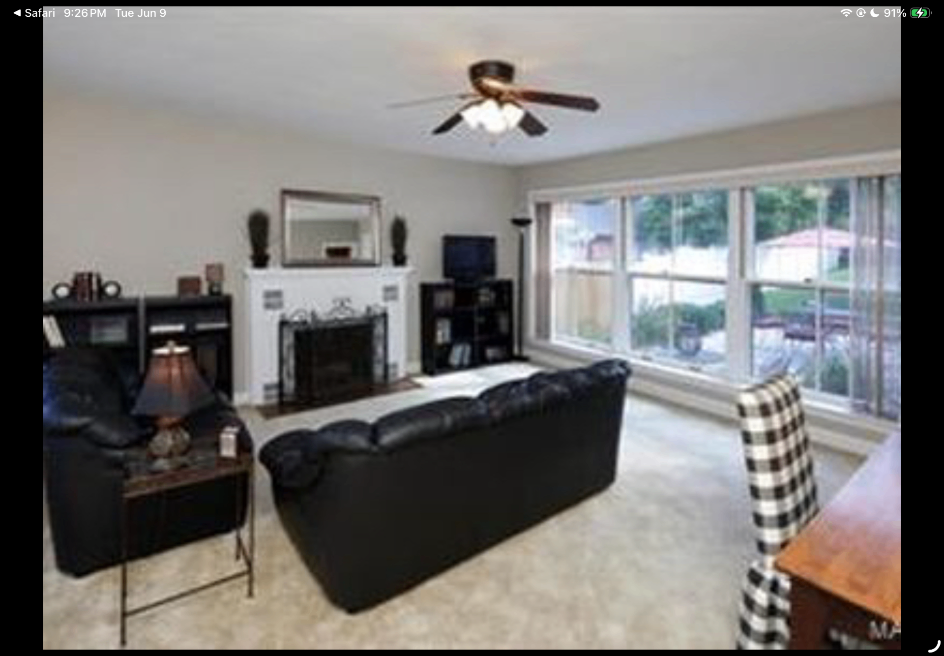 Living room with black leather seating, fireplace and oversized picture window